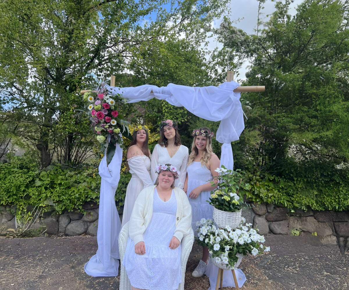 Frauen mit Haarkränzen unter Hochzeitsbogen